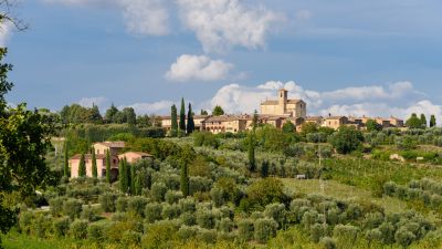 Klostret Certosa di Pontignano med odlingar och uppstickande cypresser i frgrunden.